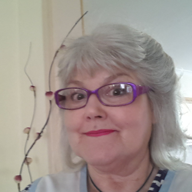 Anne Collins smiling, silver hair and purple glasses