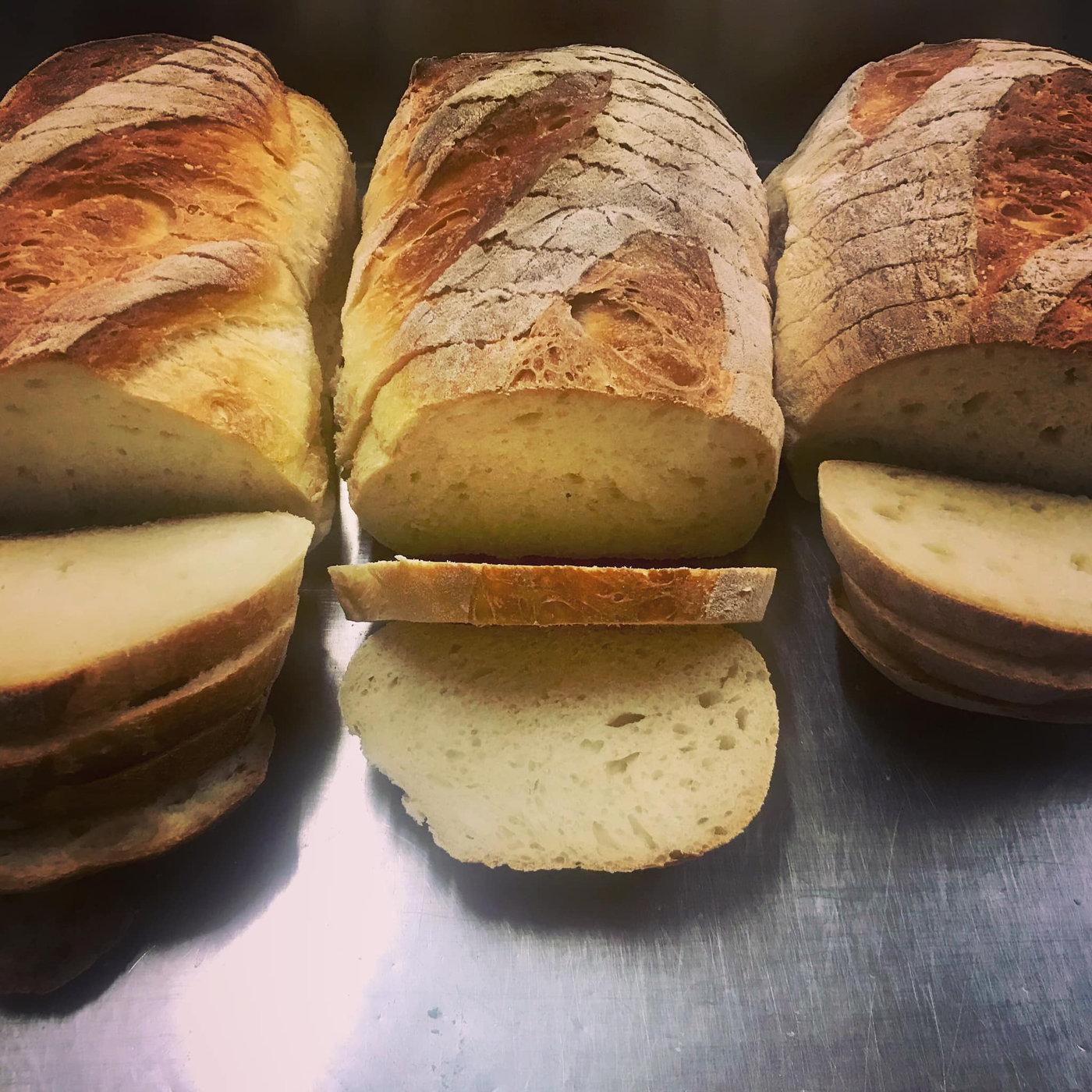 White Vienna sourdough loaves on the rack, one sliced