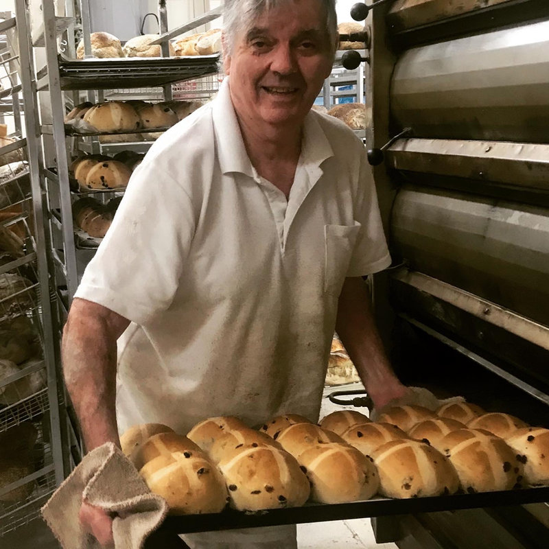 Danny Collins sliding a tray of hot cross buns from the oven