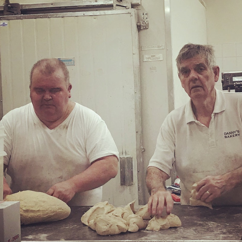 Jesse and Danny hand-moulding loaves at the bench