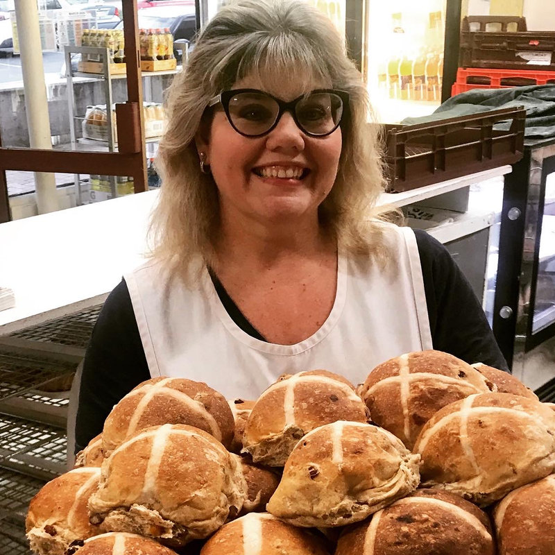 Katie smiling behind a stack of giant hot cross buns