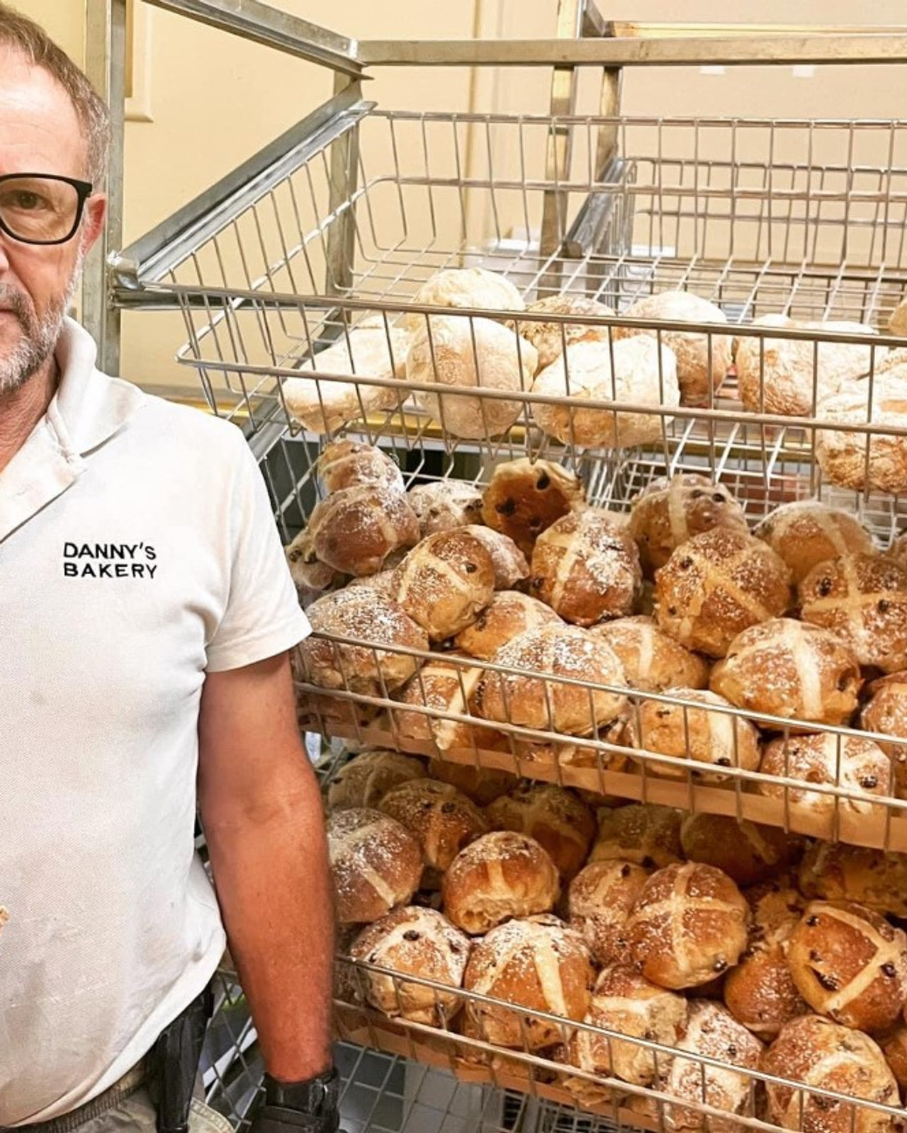 Wayne beside a wire rack of hot cross buns